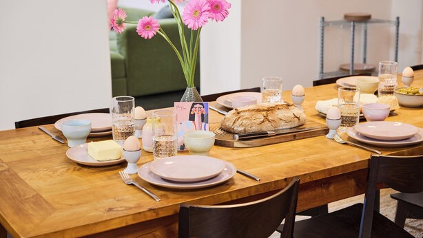 A dining table set with plates, glasses, a loaf of bread, and a vase with flowers. - Poets Place | Design Apartment in Kreuzberg (Berlin)