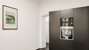 A modern kitchen with a large refrigerator and oven, a framed picture on the wall, and a dark wooden floor. - Poets Place | Design Apartment in Kreuzberg (Berlin)