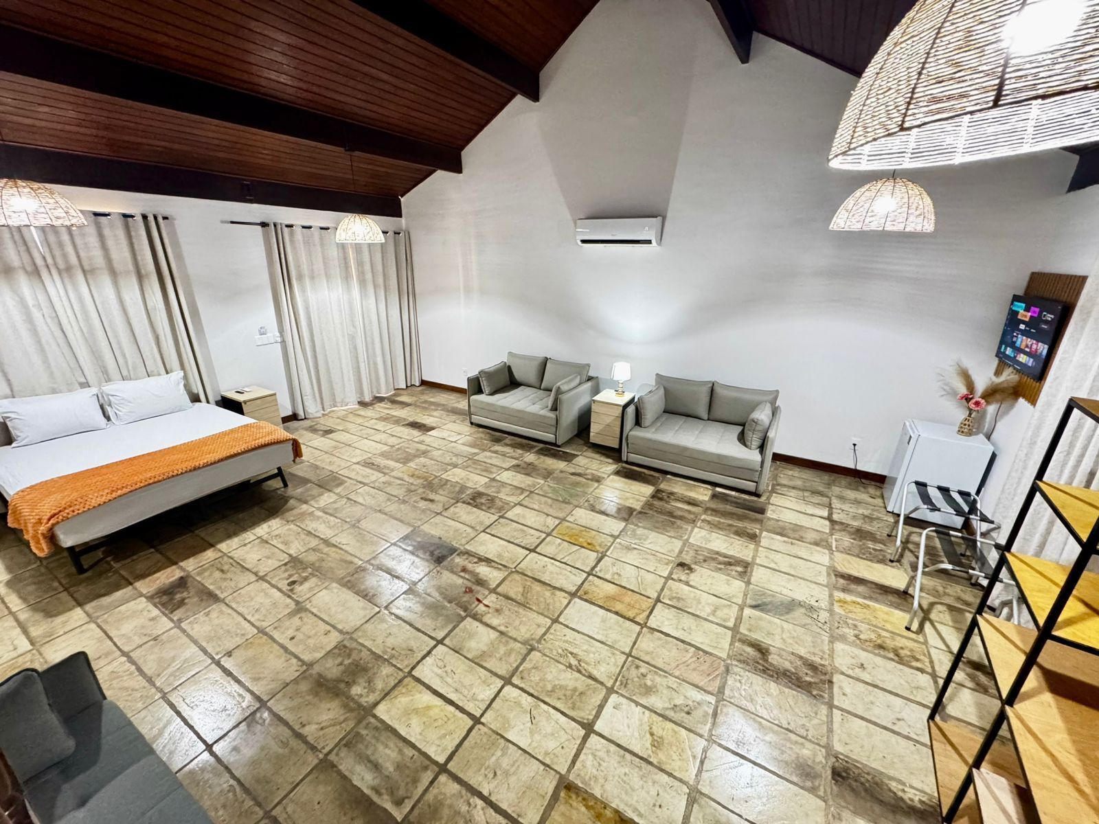 Una habitación amplia con una cama, dos sofás, una mesita y un televisor.