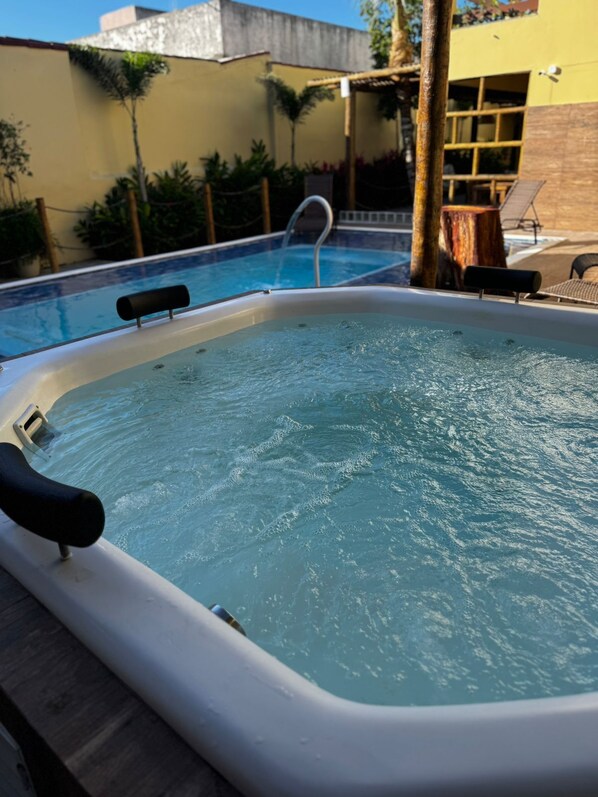 A hot tub with a ladder, surrounded by a pool and outdoor furniture. - Pousada Caminho da Passagem (Cabo Frio)