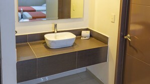 A bathroom with a white sink, a mirror, and a door. - Motel & Hotel Nivel 10 (Manzanillo)