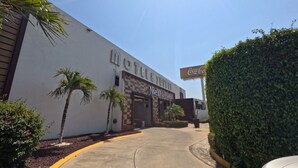 A motel with a Coca-Cola sign, palm trees, and a clear sky. - Motel & Hotel Nivel 10 (Manzanillo)
