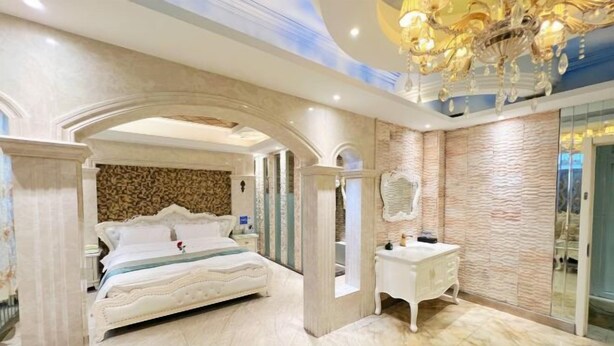 A bedroom with a large bed, a vanity, and a chandelier. - No.5 Theme Hotel (Yanji)