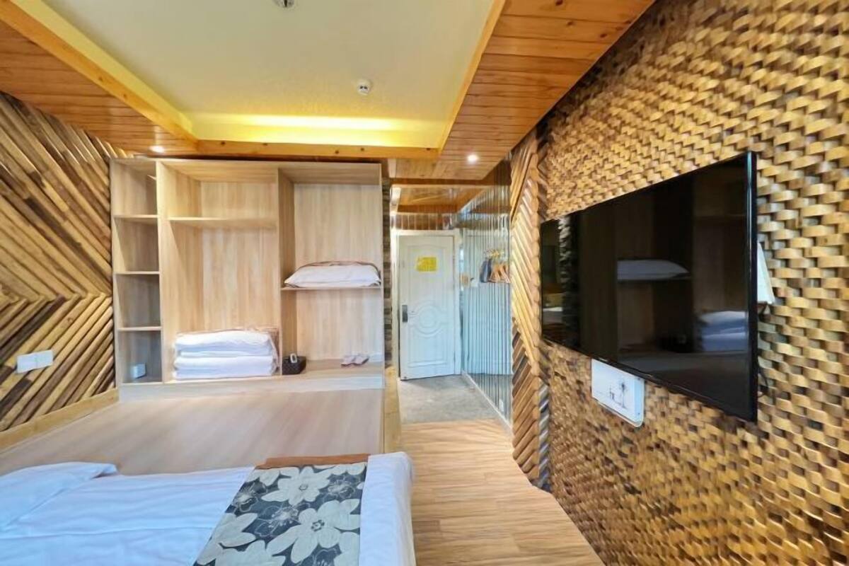 A room with a bed, wooden walls, a television, and a wardrobe.