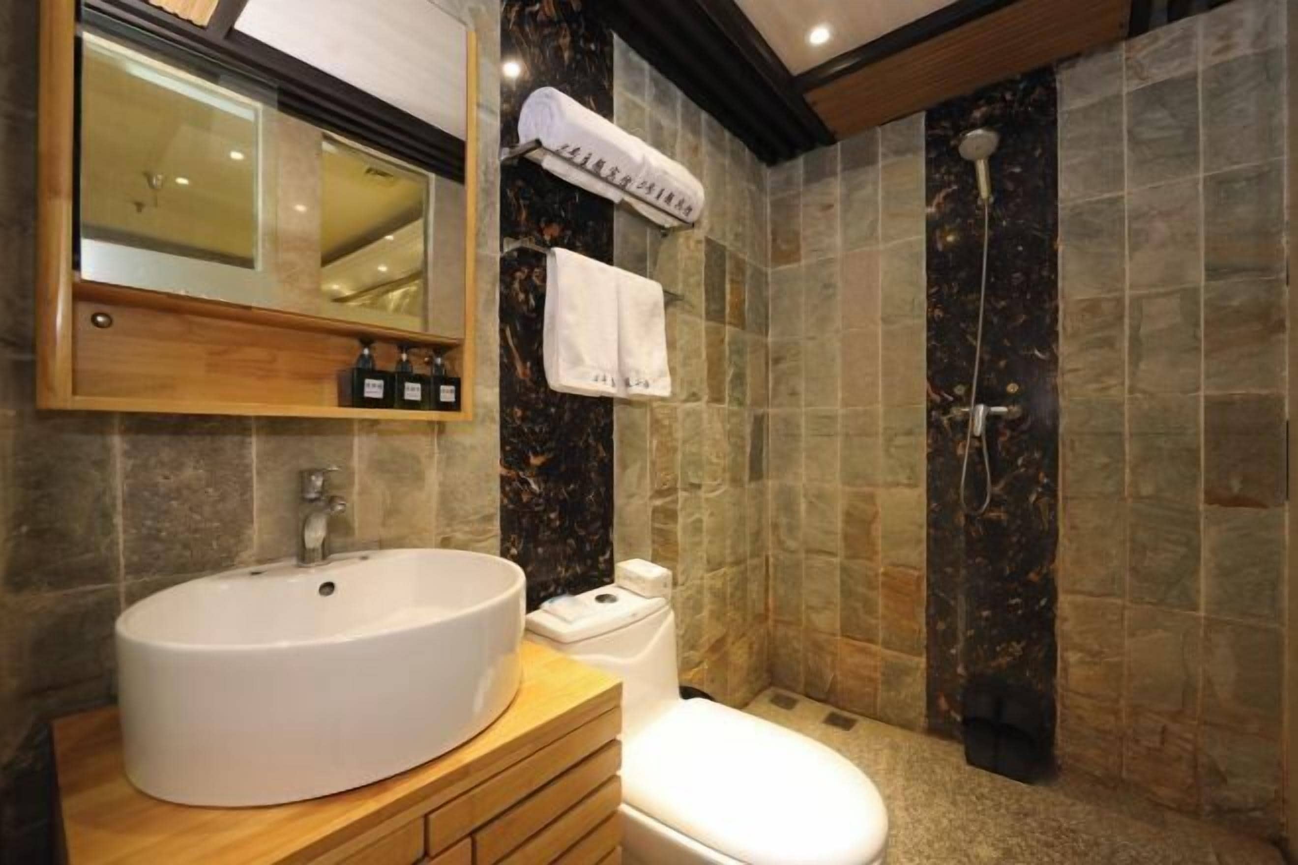 A bathroom with a white sink, a toilet, a mirror, and a shower.