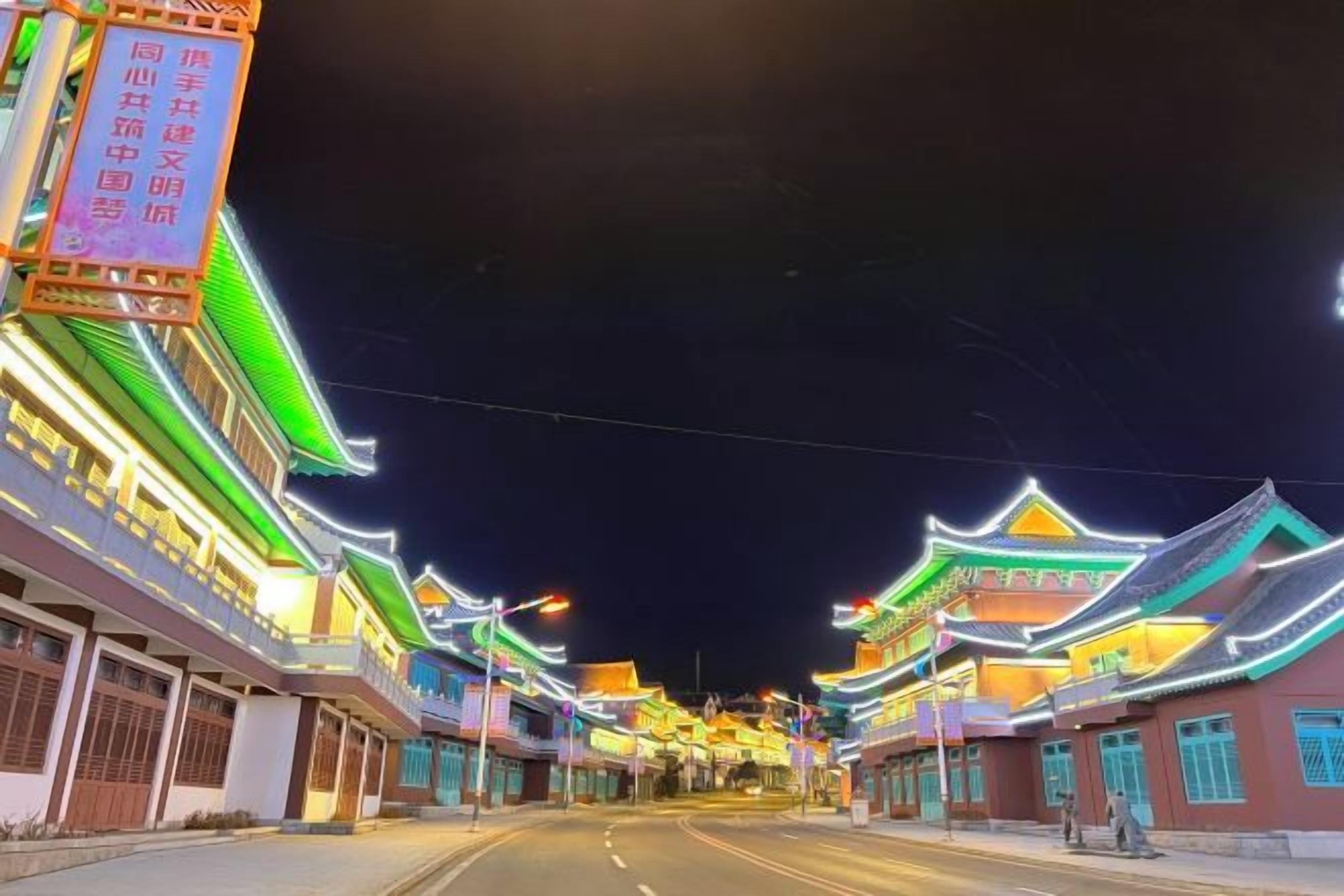 A street lined with traditional buildings with illuminated signs.