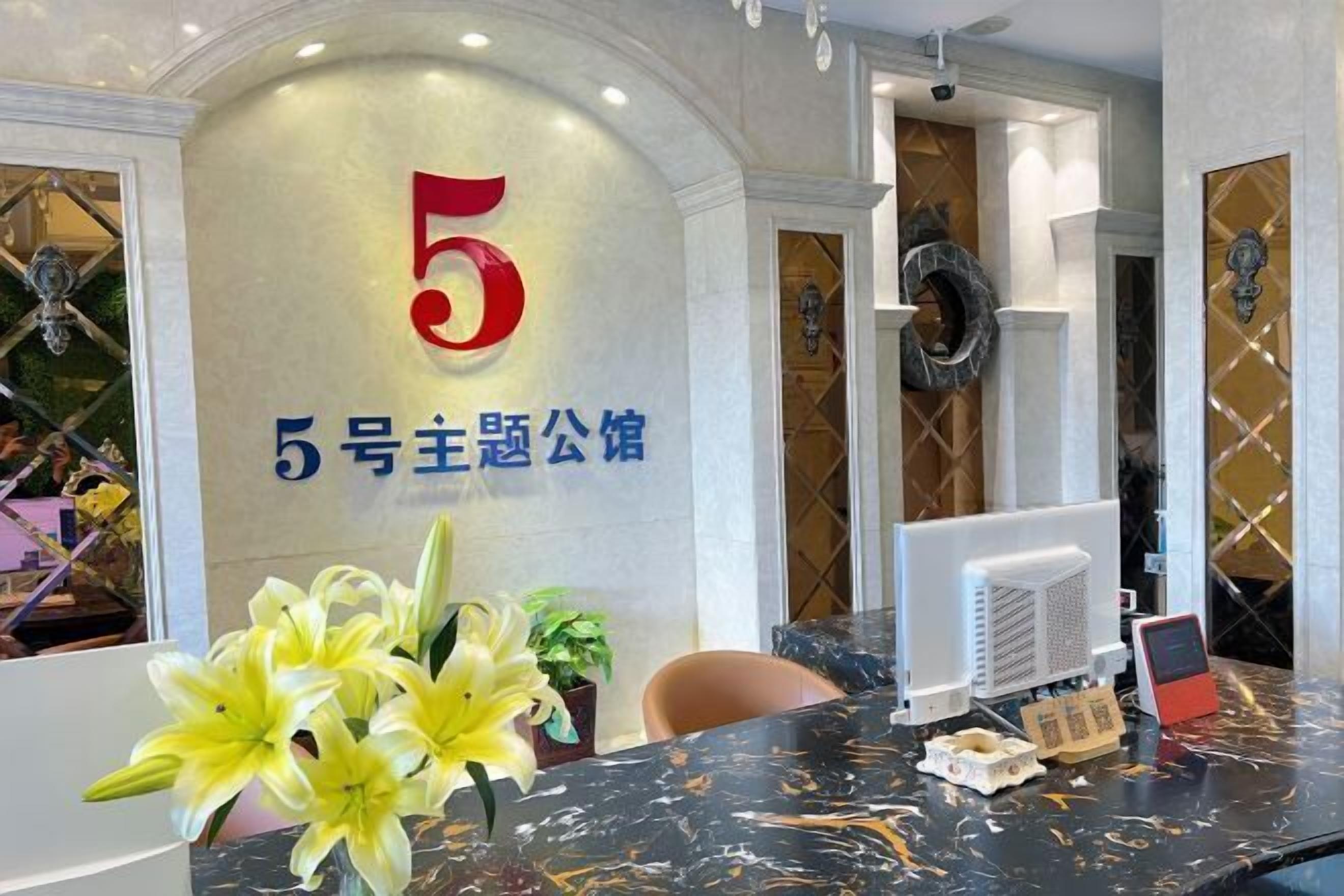 A reception desk with a large number '5' sign, a computer, and a small plant.