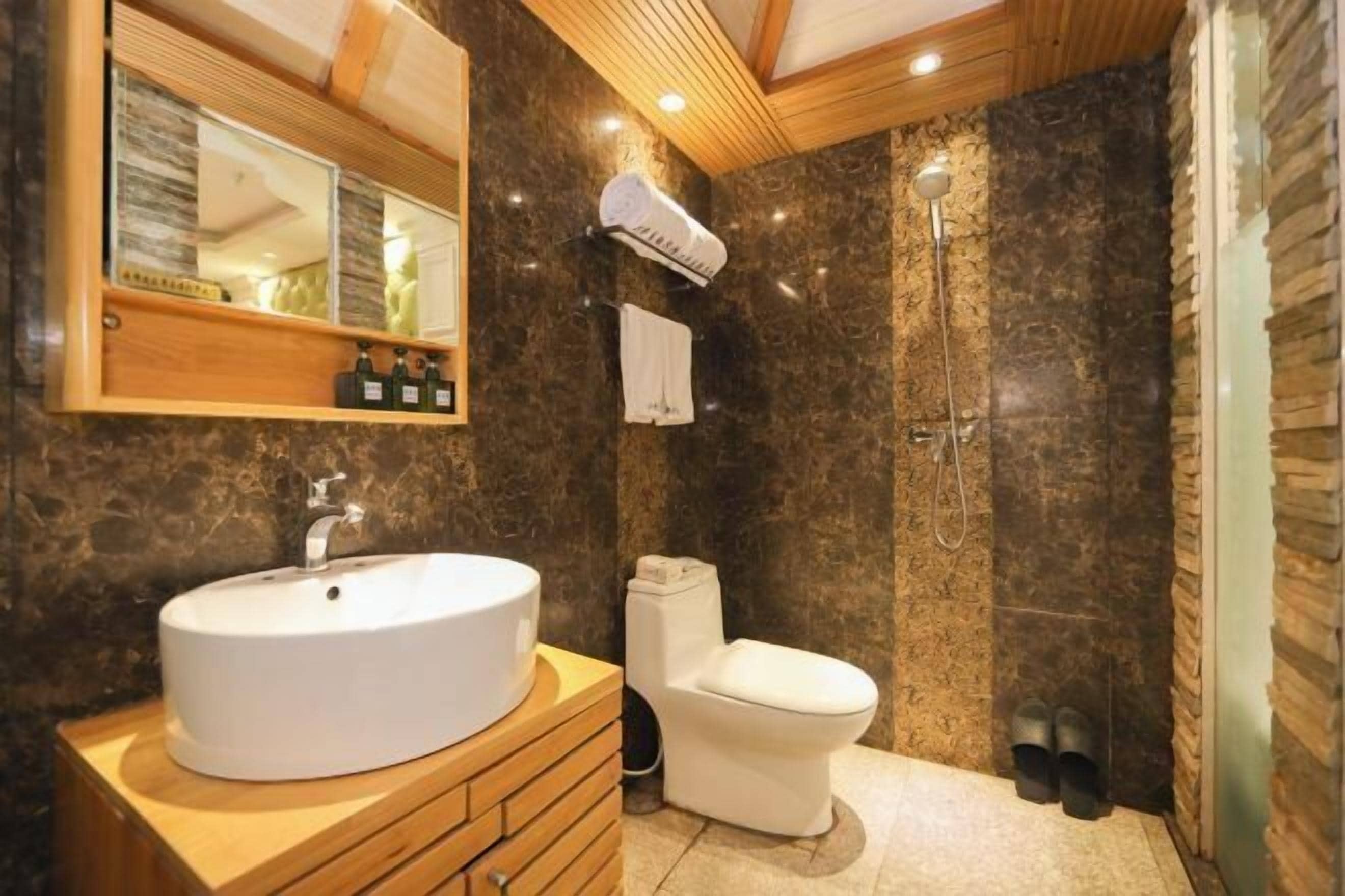 A bathroom with a round sink, toilet, and shower.