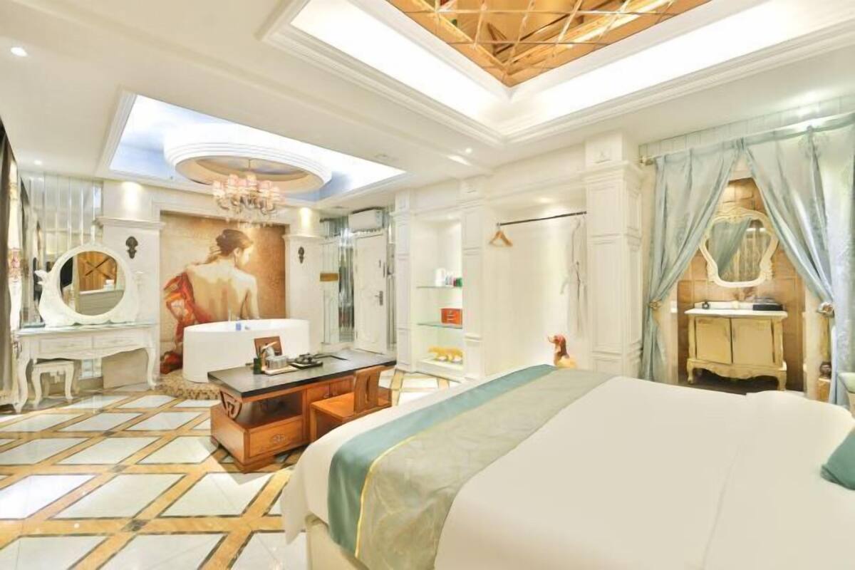 A spacious bedroom with a large bed, a vanity with a mirror, and a chandelier.