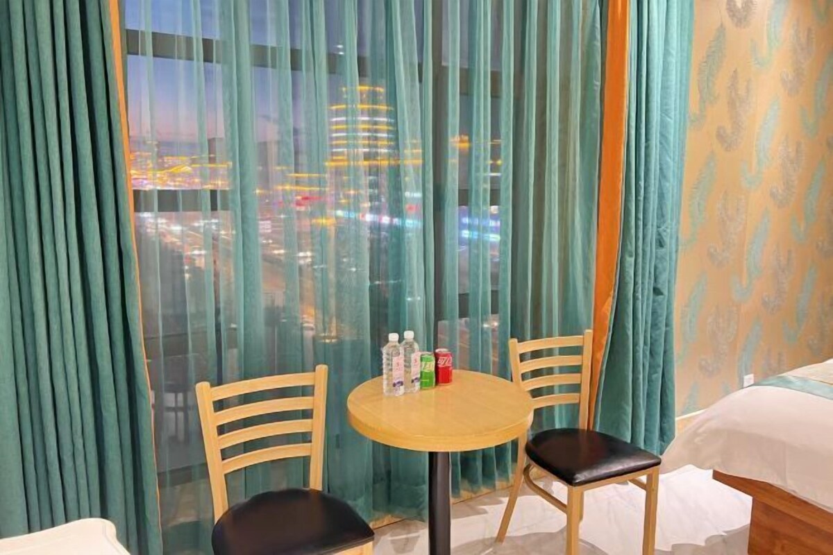 A hotel room with a city view, a round table with chairs, and a bed.