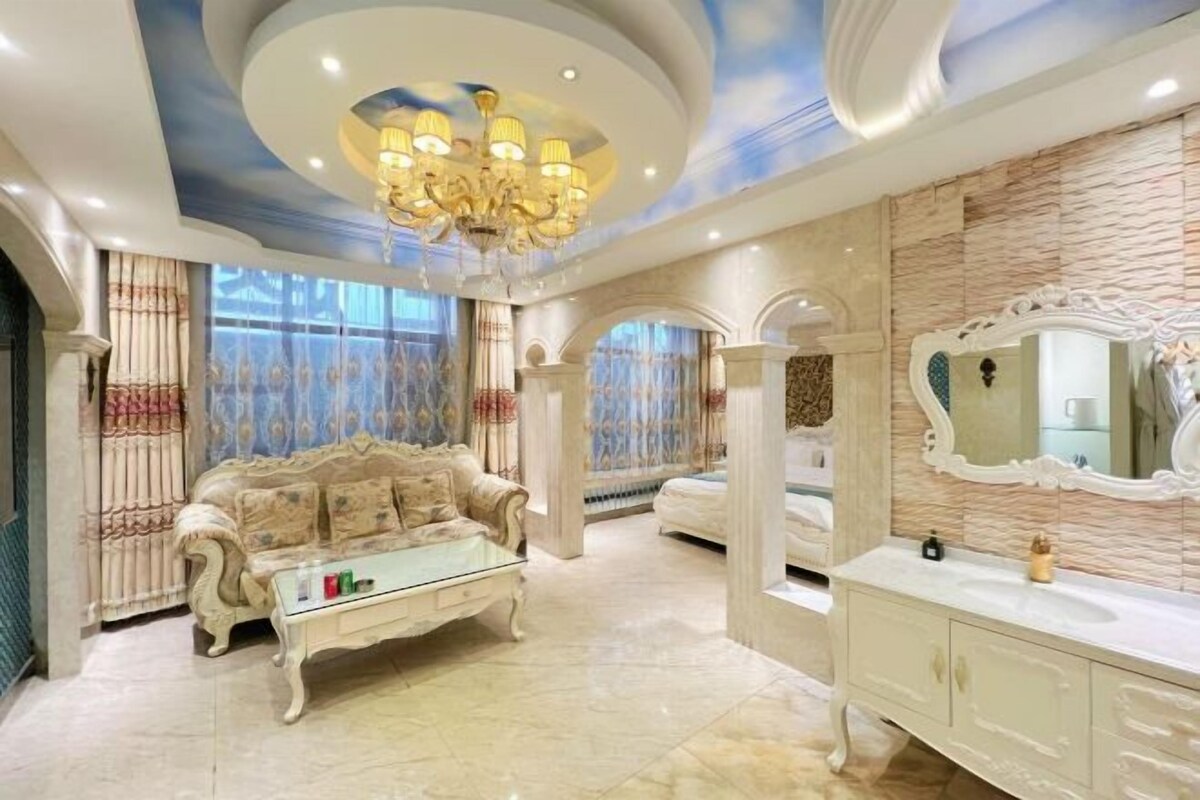 A luxurious room with a classic sofa, a glass coffee table, a white vanity with a mirror, and a decorative ceiling.