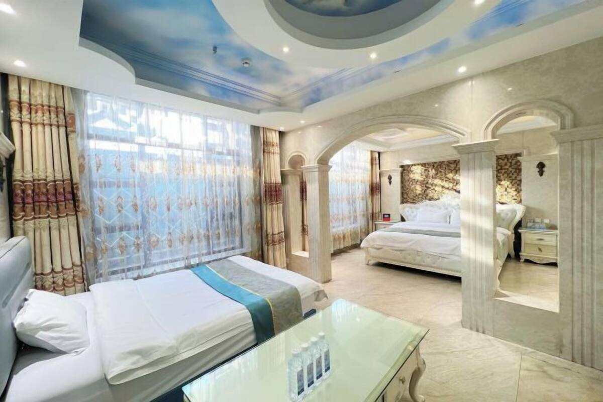 A hotel room with a large bed, a separate sitting area, and a view of the outside.
