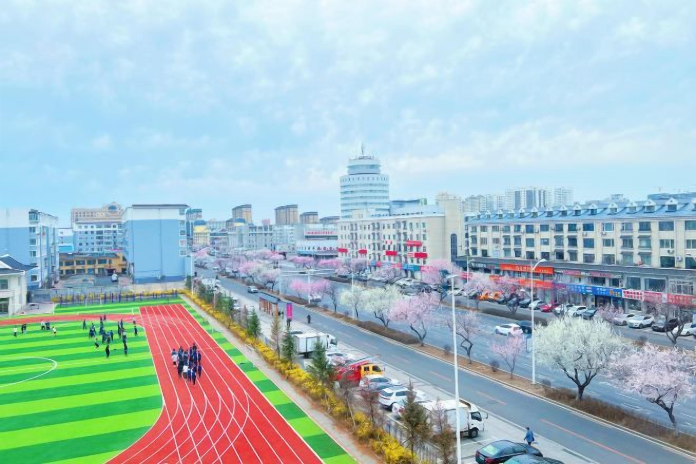 Un paisaje urbano con una pista de atletismo, edificios y una carretera con vehículos.