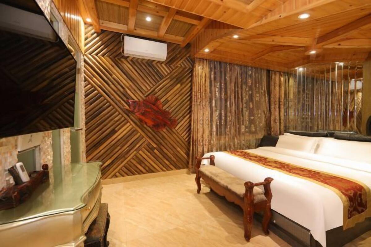A wooden ceiling, a bed with a white and red bedspread, and a wooden bench.