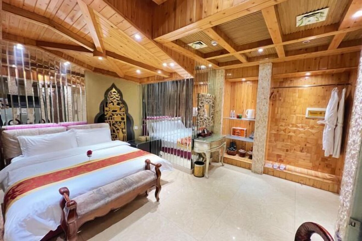 A wooden-floored room with a large bed, a small table, and a wooden cabinet.