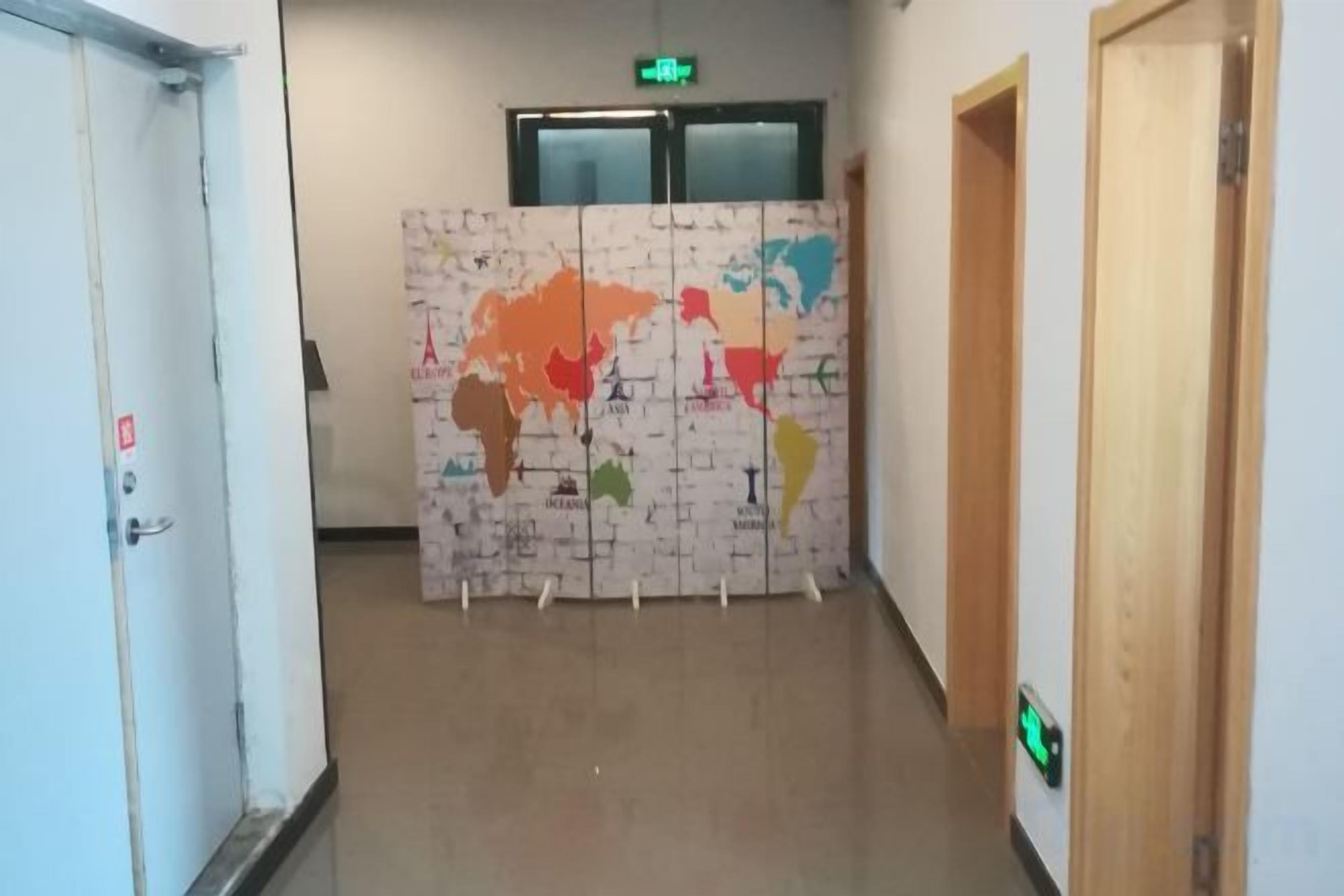 Un pasillo con un mural de mapa mundial, puertas y una señal de salida.