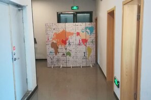 Un corridoio con una carta del mondo dipinta al muro, porte e un segnale di uscita.