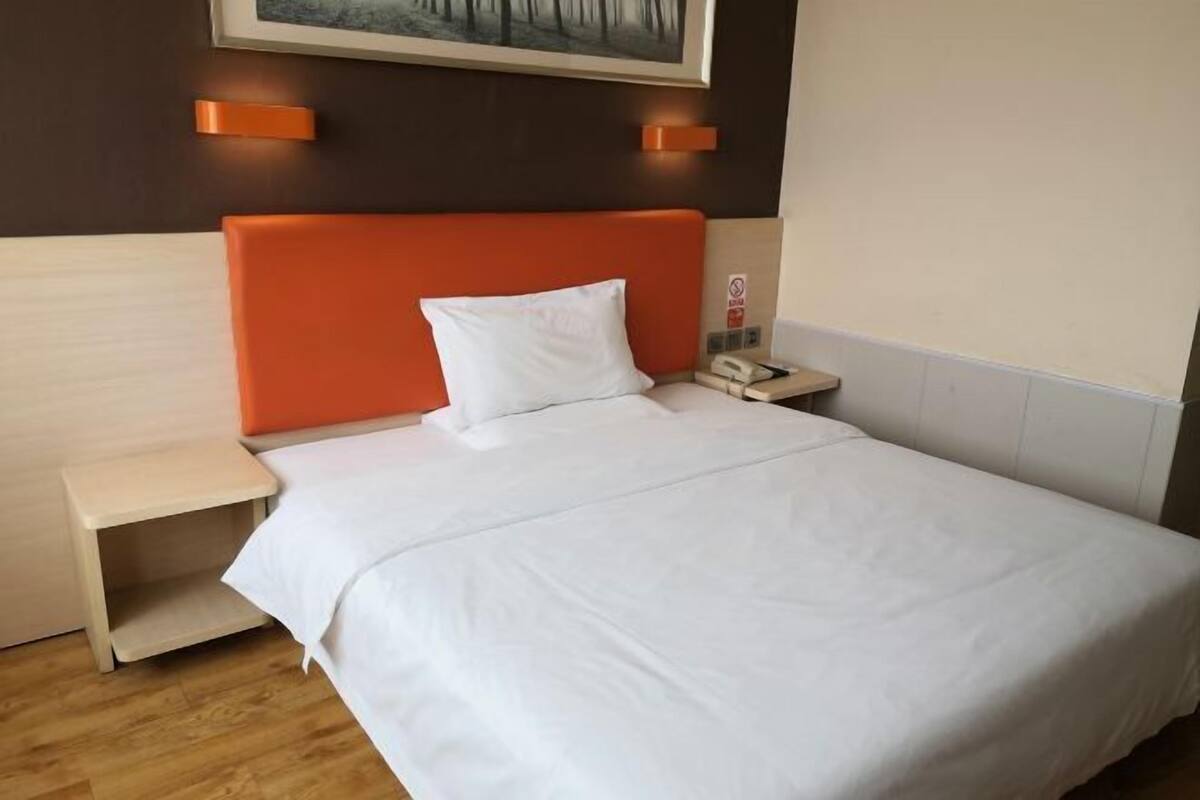 A hotel room with a bed, a nightstand, and a telephone.