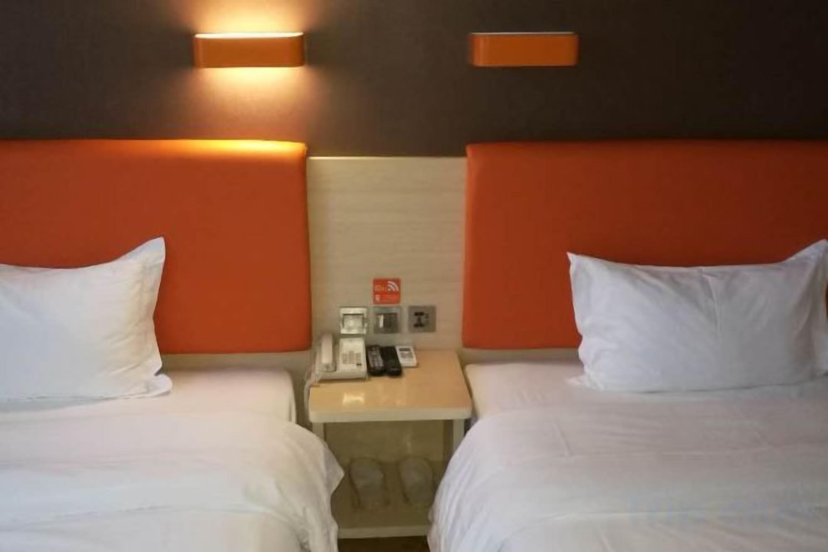 Camera d'albergo con due letti, un comodino e un telefono fissato alla parete.
