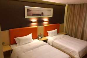 Camera d'albergo con due letti, entrambi con biancheria bianca e testate arancioni. Sopra i letti, un quadro incorniciato a parete, e un telefono sul comodino.