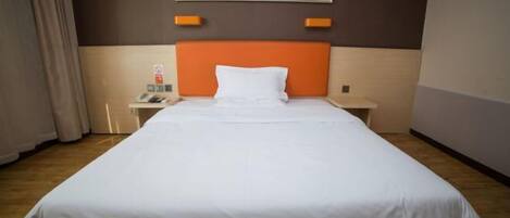 Una habitación de hotel con una cama grande, una mesita de noche con un teléfono y un cuadro en la pared.