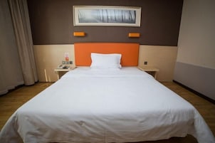 Una habitación de hotel con una cama grande, una mesita de noche con un teléfono y un cuadro en la pared.