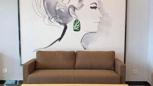 A room with a brown sofa and a wooden table in front of a wall with a partial painting of a woman's profile. - Enjoy staying at Premium Hotel (Zhaoyuan)