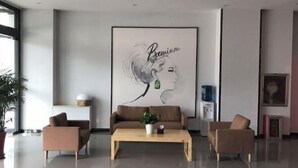 A modern lobby with a large framed artwork, two sofas, a coffee table, and a potted plant. - Enjoy staying at Premium Hotel (Zhaoyuan)