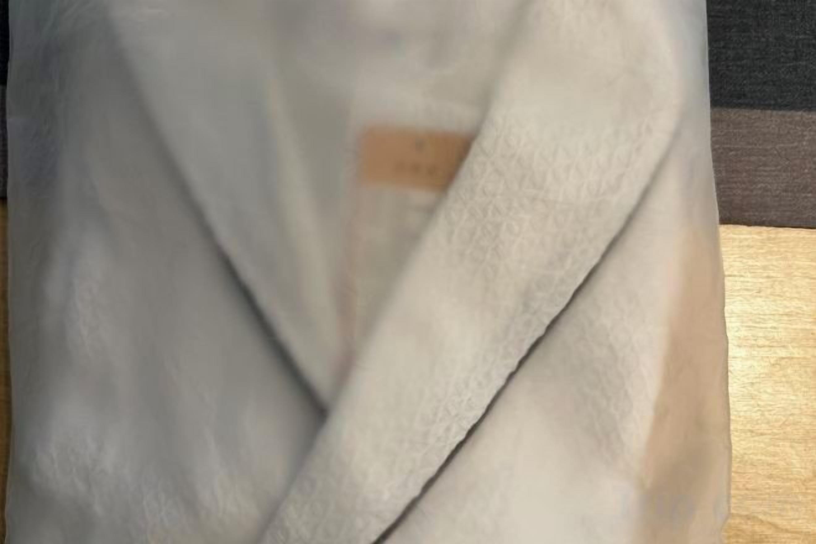 Een witte, gebreide stof, mogelijk een handdoek of deken, met een etiket.