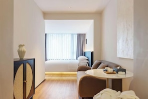 Ein modernes Hotelzimmer mit Bett, Sofa, einem kleinen runden Tisch und einem Schrank.