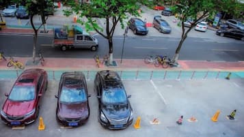 A parking lot with cars and a bicycle, trees, and a sidewalk.