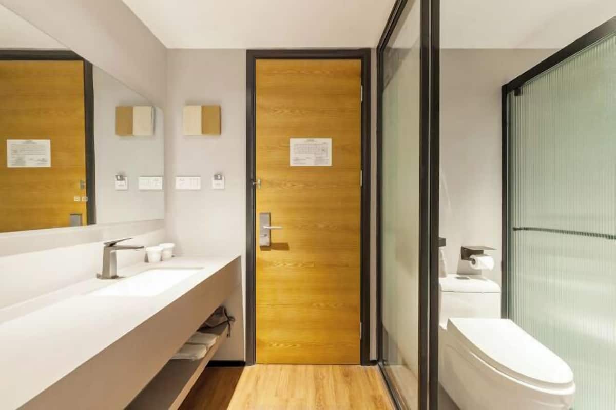 A modern bathroom with a wooden door, a white sink, and a toilet.