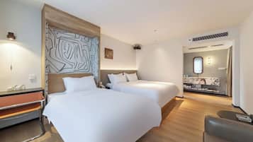 A hotel room with two beds, a desk, and a seating area.
