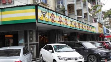 A storefront with a green and yellow awning, a sign with Chinese characters, and several parked cars in front.