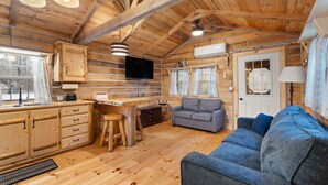 A cabin interior with a wooden interior, a sofa, a dining table, and a TV.