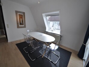 A modern room with a white table, clear chairs, a black mat, a framed picture, and a window with a view. - Apartment Near Albert Beach Knokke (Knokke-Heist)