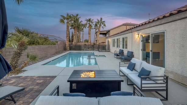 Un jardin avec une piscine, un espace salon extérieur et des palmiers.