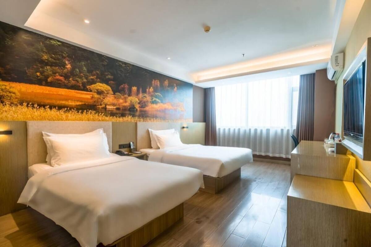 A hotel room with two beds, a large window, a painting on the wall, and a small desk.