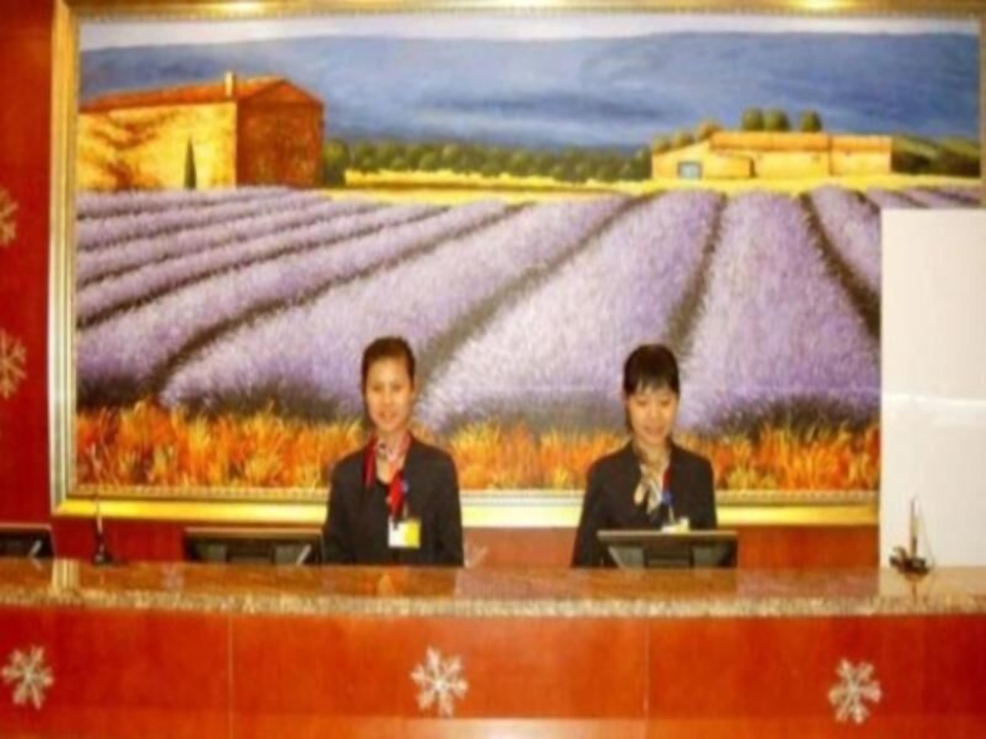 Dos personas sentadas en la recepción, con un campo de lavanda y un edificio de fondo.