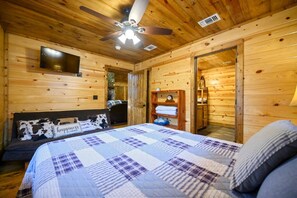 A wooden cabin bedroom with a bed, a ceiling fan, a TV, and a wooden wardrobe. - Whitetail Retreat Cabin for 13! (Broken Bow)