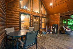 A log cabin with a dining area featuring a table and chairs, large windows, and a door. - Whitetail Retreat Cabin for 13! (Broken Bow)