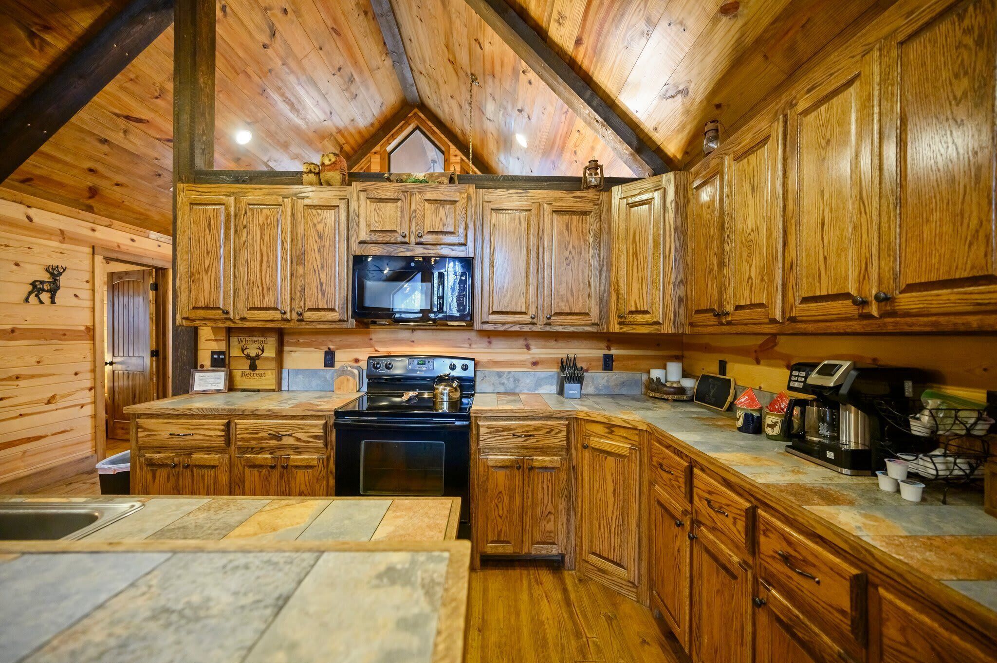 A wooden cabin interior with a kitchen area featuring a stove, microwave, and coffee machine.