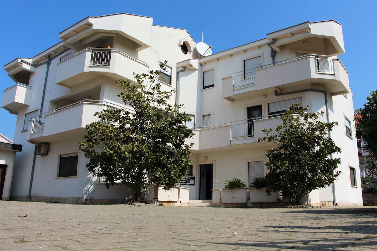 A multi-story building with balconies and a paved courtyard.