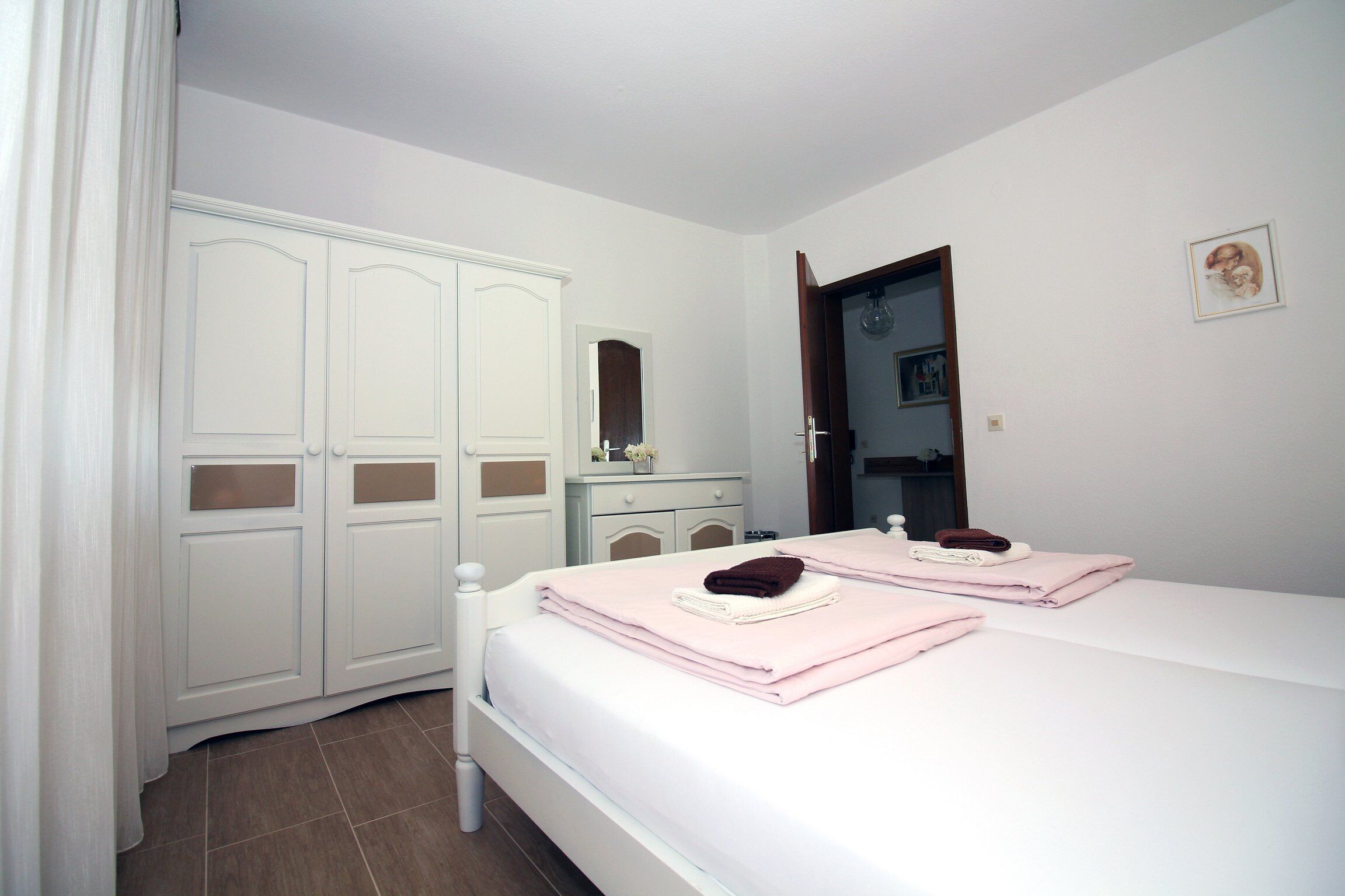 Un dormitorio con dos camas, un armario, una cómoda y un espejo.