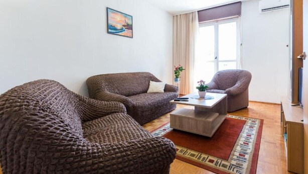 Een gezellige woonkamer met twee gestreepte banken, een salontafel en een hanglamp.