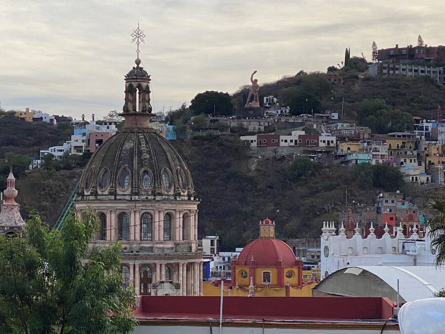 A historic building with a prominent dome and bell tower, surrounded by residential buildings on a hillside.