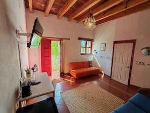 A living room with a TV, sofa, and a door leading outside.
