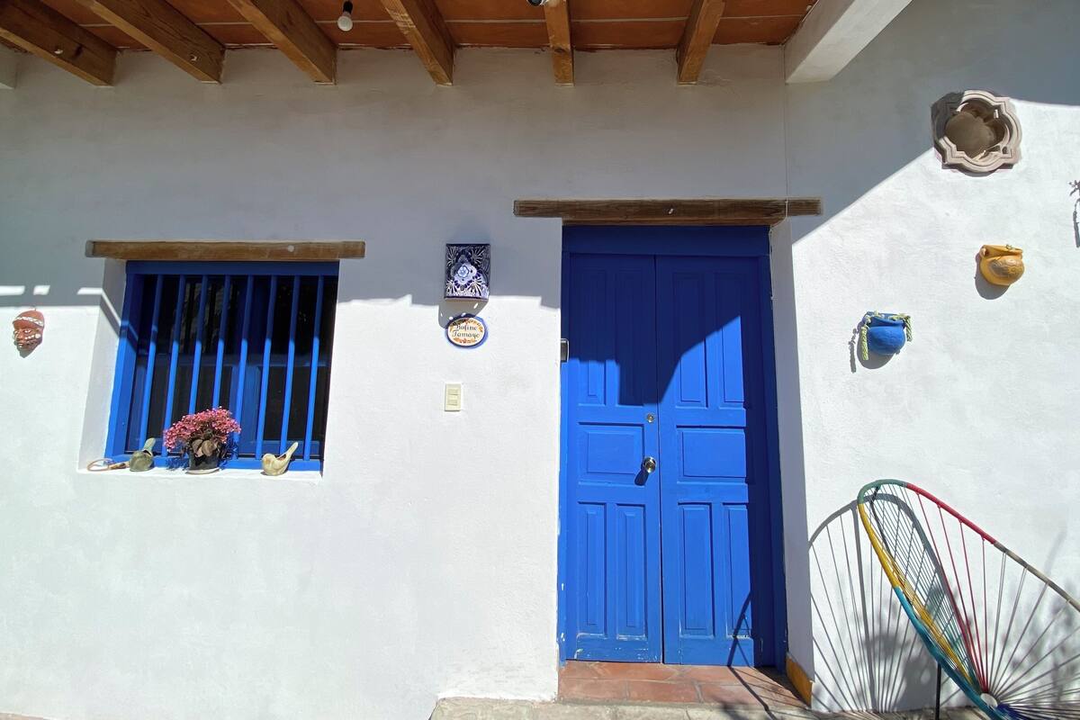 A building with a blue door, a window with blue shutters, and a wall-mounted light fixture.