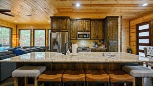 Una cocina amplia con armarios de madera, una isla grande con taburetes de bar y un microondas integrado.