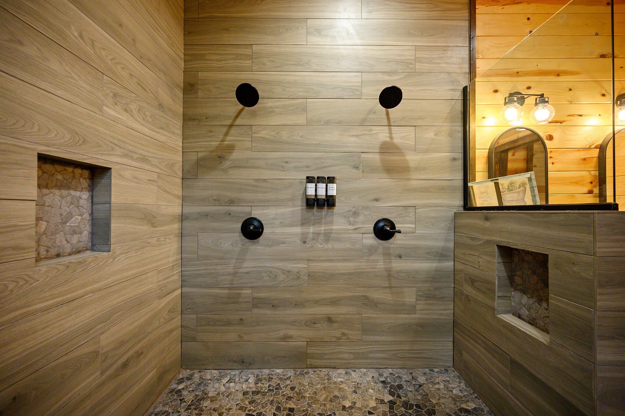Un baño moderno con paredes de madera, una pared de acento de piedra y un espejo con iluminación.